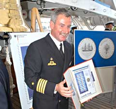 Kapitän zur See Norbert Schatz präsentiert die neue Briefmarke und die Gorch-Fock-Gedenkmünze